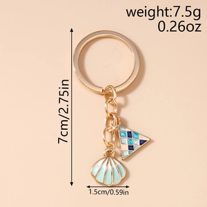 Close-up of golden keychain with blue tile triangle and seashell charm showing 7cm length