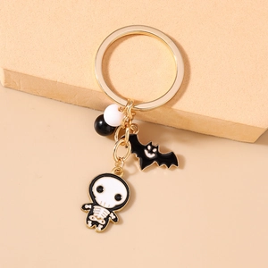 Detailed view of Halloween keychain with black enamel bat and skeleton charms on gold ring