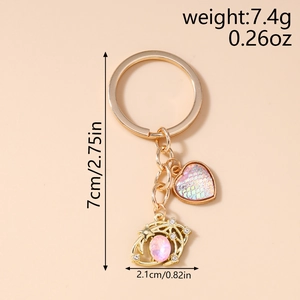 Detailed close-up of golden keychain with pink heart charm and crystal planet pendant