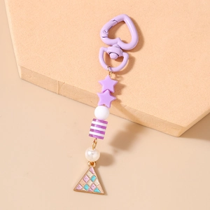 Dettaglio del portachiavi con perline viola, ciondoli a stella e pendente a triangolo su base