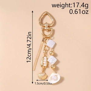 Detail view of gold ocean keychain with heart clasp, pearls, shells and beaded tassel