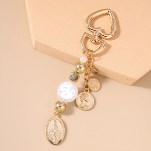 Detail of vintage gold keychain with religious medal, pearl beads and heart clasp