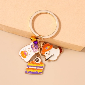 Detail of Halloween keychain charms with ghost, spooky cake, gold bell and purple bow