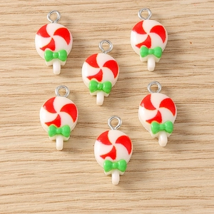 Close-up of red and white spiral lollipop resin charms with green bows for DIY jewelry