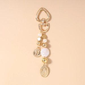 Detail view of heart-shaped gold clasp with coin pendant and faux pearl beads