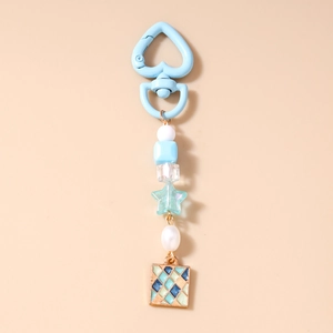 Dettaglio del portachiavi con chiusura a cuore blu chiaro, perle e ciondolo a scacchi