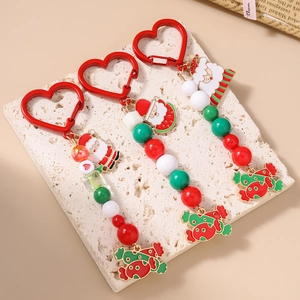 Christmas beaded keychains with Santa Claus and candy pendants on beige stone background