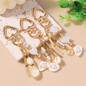 Ocean theme keychain with gold tassels, pearls, and seashells on a stone surface