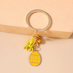 Detail of yellow octopus keychain with decorative painted egg and golden bell pendant