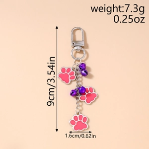 Detail view of pink enamel cat paw pendants and purple bells with measurement markings