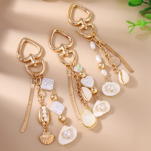 Detail of ocean-style gold heart carabiner with pearls and shells for handbags