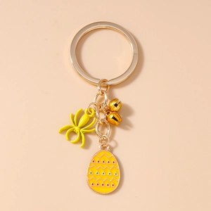 Detail of yellow spider charm, bells and festive egg pendant on gold keychain ring