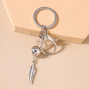 Détail d'un porte-clés bohème avec plume en métal sculpté et perles de turquoise lisses