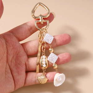 Detail of ocean-themed keychain with golden shells, pearls, and beaded heart clasp charm