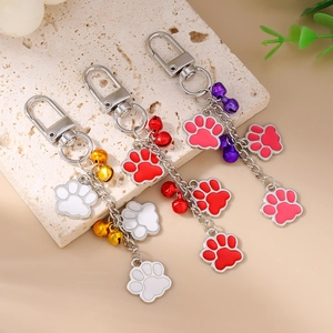 Cute paw print keychain set with colorful bells and cat charms on a stone surface
