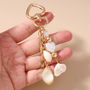 Detailed macro view of heart-shaped gold keychain with pearls and ocean shell pendants