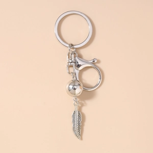 Détail du porte-clés bohème en métal argenté avec pendentif plume et perle décorative