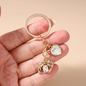 Detail of gold heart keychain with iridescent scales and crystal moon charm