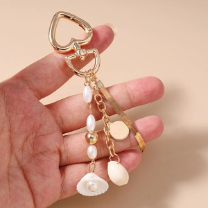 Macro shot of gold-plated ocean-themed keychain with tassels, pearls and sea shells