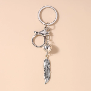 Gros plan détaillé d'un porte-clés plume vintage en argent avec une perle en métal