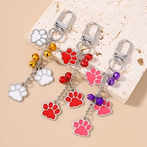 Cute cat paw keychain set with colorful bells and enamel charms on stone display