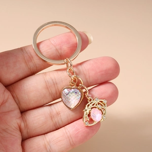 Detail of hand holding a golden heart and star keychain with iridescent scale texture