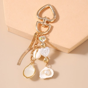 Detail of ocean-themed keychain with gold heart clasp, shell pendants, and pearls