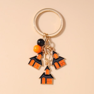 Detail of Halloween keychain featuring gold rings and three orange and black haunted houses
