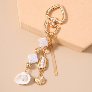 Close-up of ocean-themed keychain with gold shell, pearls, and tassel charms