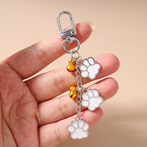 Detail of silver lobster clasp keychain with cat paw charms and golden bells in hand