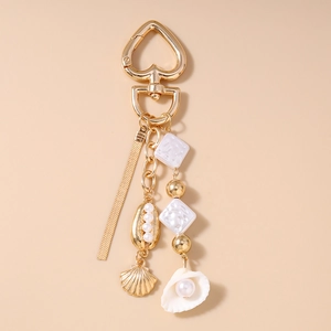 Detail of ocean-themed keychain featuring gold shells and white pearls with tassel