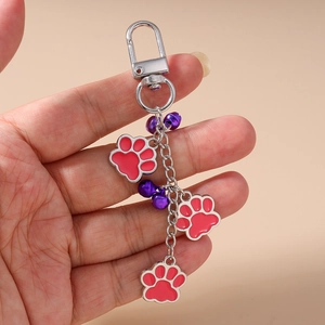 Close-up of silver paw print keychain with red enamel charms and small purple bells