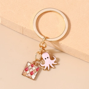 Detail of pink octopus and red checkered enamel charms on a gold-tone keyring
