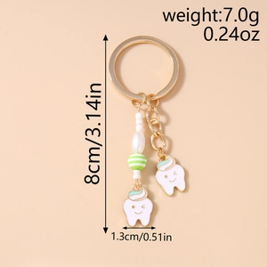 Detail of cute tooth-shaped charms keychain with striped green beads and gold ring