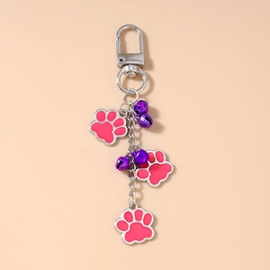 Detail of cute paw print keychains featuring pink enamel charms and purple bells