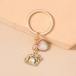 Detailed close-up of golden keychain with iridescent heart and star-shaped charms on warm background