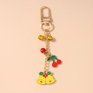 Détail du porte-clés cloche de Noël doré avec pendentifs baies rouges et cerises