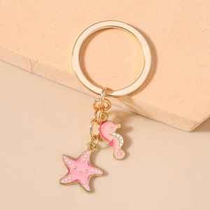 Detailed macro view of gold-plated enamel sea horse and starfish keychain charms