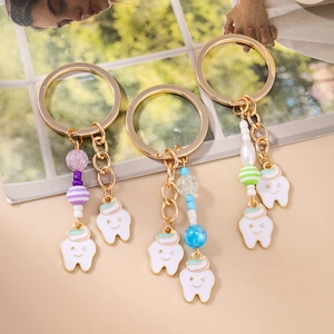 Three striped beaded tooth keychains with smiling pendants and colorful charms
