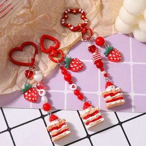 Three strawberry cream cake keychains with heart beads and red heart-shaped hooks for bags