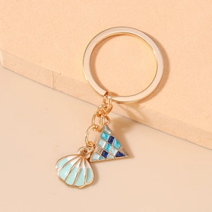 Detail of golden ocean style keychain featuring a mint green shell and geometric charms