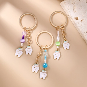 Three cute striped beaded tooth enamel keychains with smiling faces on beige background