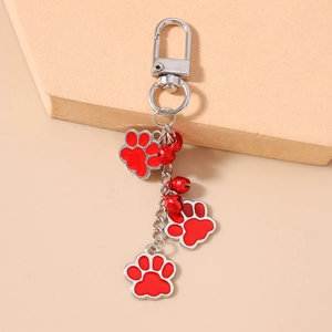 Close-up of red paw print keychains with matching bells and silver carabiner hook