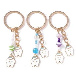 Three cute tooth keychains with colorful beads and smiley faces on white background