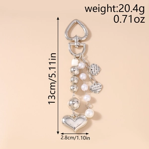 Détail d'un porte-clés en cœur avec gravure love you et perles d'imitation blanches