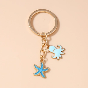 Detailed view of gold ocean keychain with blue octopus and starfish charms on orange background