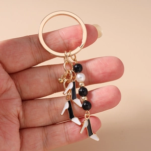 Détail de breloques escarpins et de perles sur un porte-clés doré tenu en main