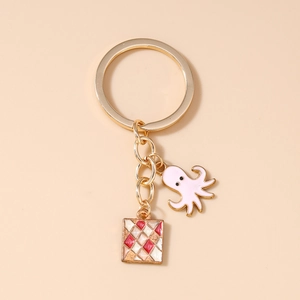 Detailed shot of a gold keychain featuring a pink octopus charm and geometric enamel square