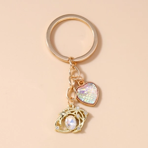 Detail of heart pendant with fish scale texture and iridescent gemstone charm on gold keychain