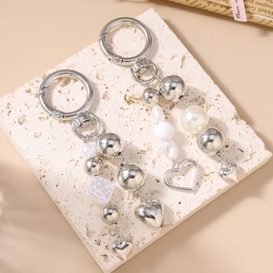 Chic silver-tone keychain with faux pearls and heart pendants on a stone display board